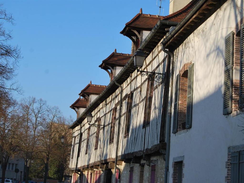 un bâtiment blanc avec des fenêtres à volets sur une rue dans l'établissement Gîte L'Arquebuse, à Troyes