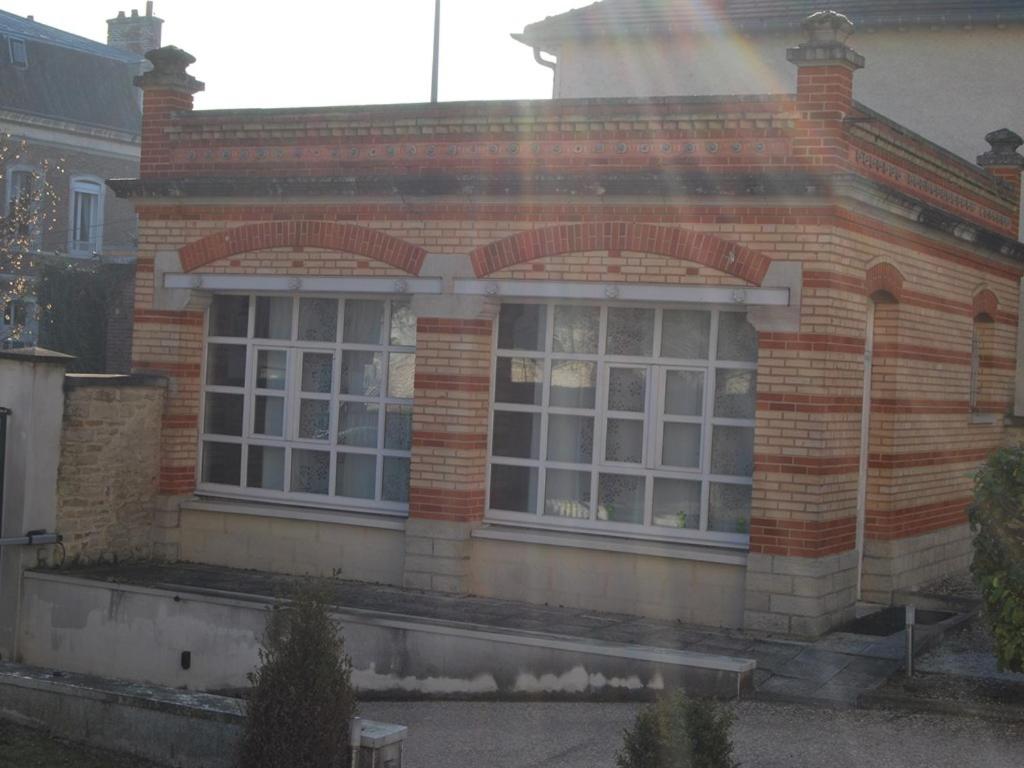 トロワにあるGîte La Tour Boileauの通りに面した大きな窓のあるレンガ造りの家