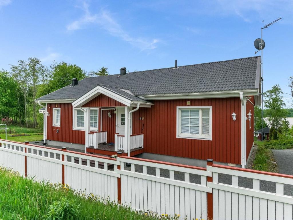 ein rotes Haus mit einem weißen Zaun davor in der Unterkunft Holiday Home Käpälämäki by Interhome in Somerniemi