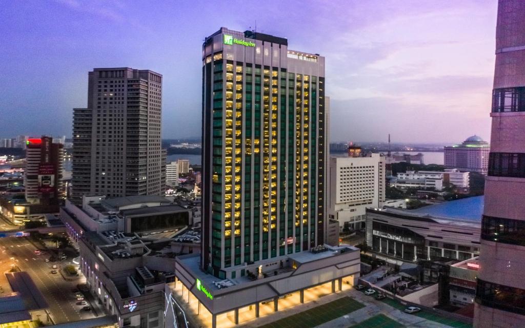 een hoog gebouw met lichten aan in een stad bij Holiday Inn Johor Bahru City Centre, an IHG Hotel in Johor Bahru