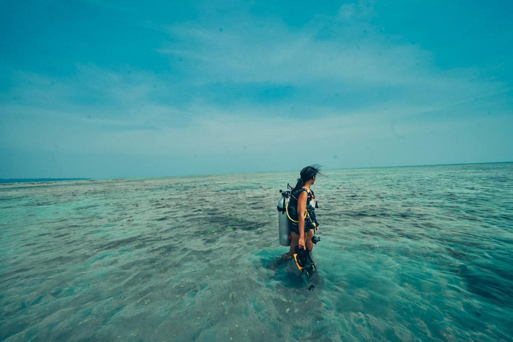 a person standing in the water in the ocean at Munjoh Ocean Resort - Private Beachfront Luxury Retreat in Havelock in Havelock Island
