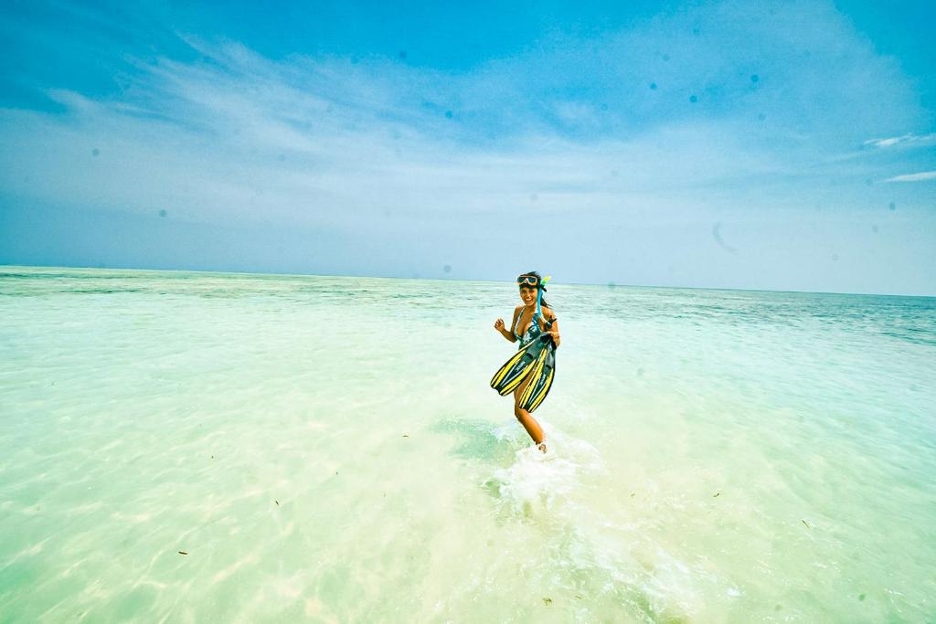 a woman running on the beach with a frisbee at Munjoh Ocean Resort - Private Beachfront Luxury Retreat in Havelock in Havelock Island