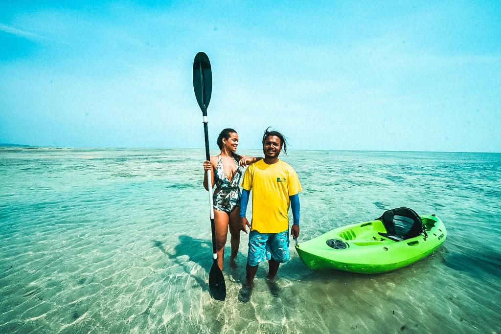 a man and woman standing in the water next to a kayak at Munjoh Ocean Resort - Private Beachfront Luxury Retreat in Havelock in Havelock Island