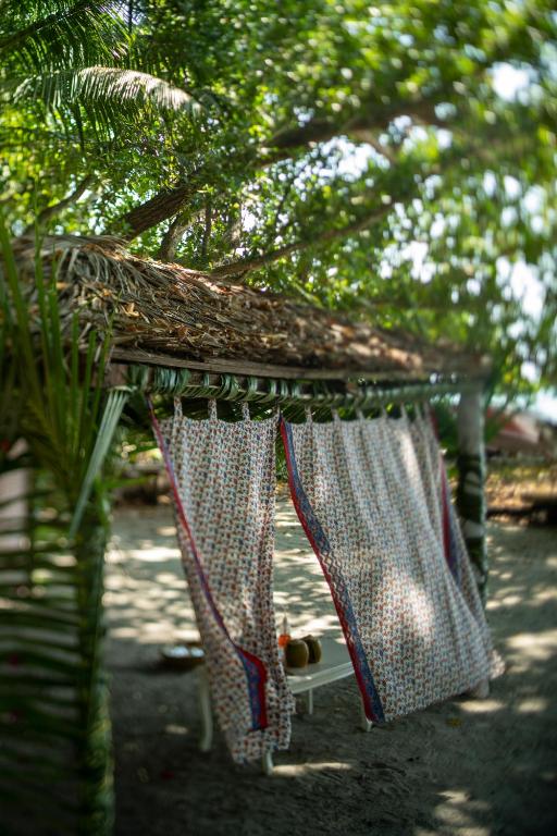 a bird feeder with a table with curtains on it at Munjoh Ocean Resort - Private Beachfront Luxury Retreat in Havelock in Havelock Island