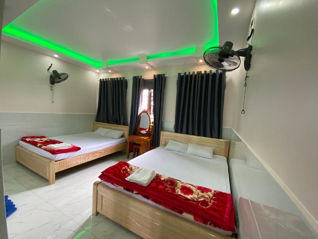 two beds in a room with green lights at Hoang Anh Hotel in Dĩ An