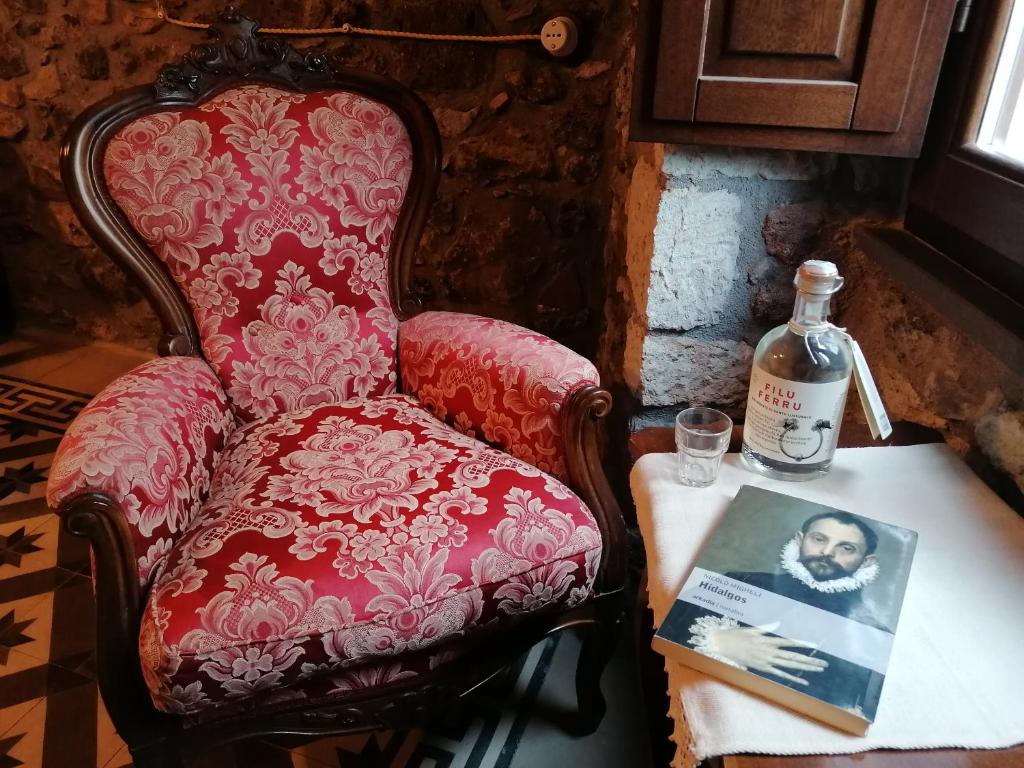 una sedia rossa seduta accanto a un tavolo con una bottiglia di whisky di Deiana a Santu Lussurgiu