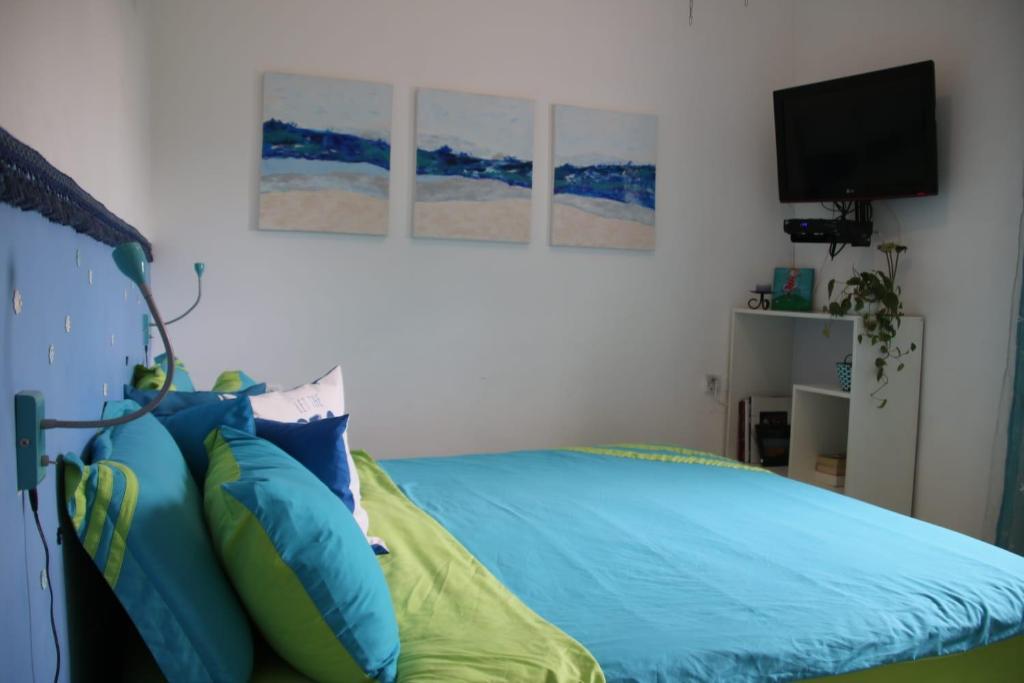 a bedroom with a bed with blue sheets and a television at Blue Lagoon with Pool in Eilat