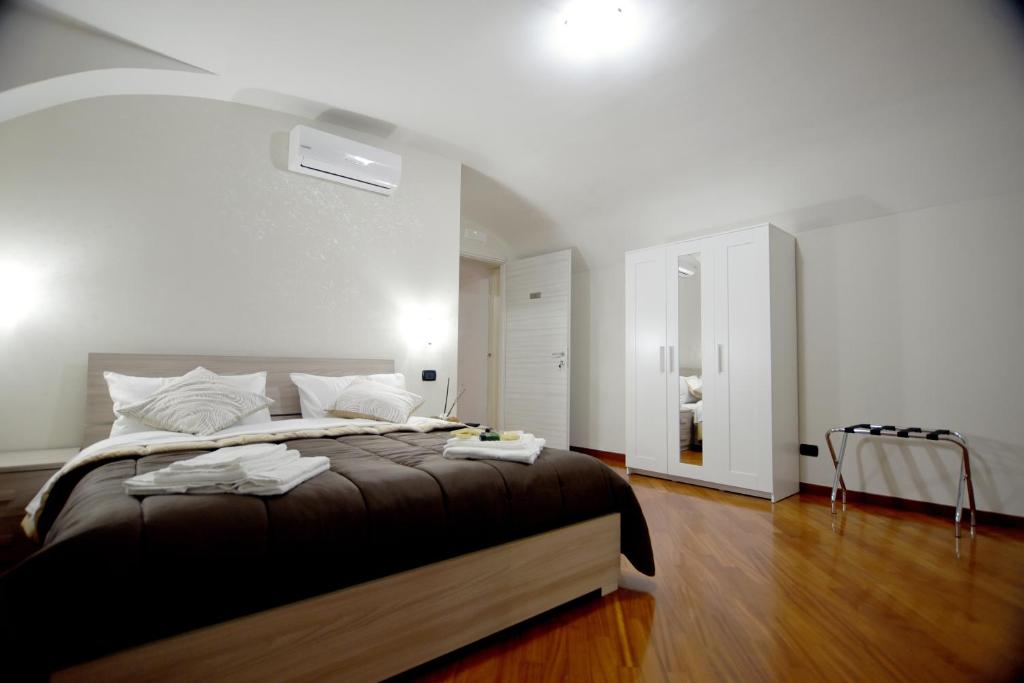 een slaapkamer met een groot bed met witte muren en houten vloeren bij Montesantogroup Apartments in Napels