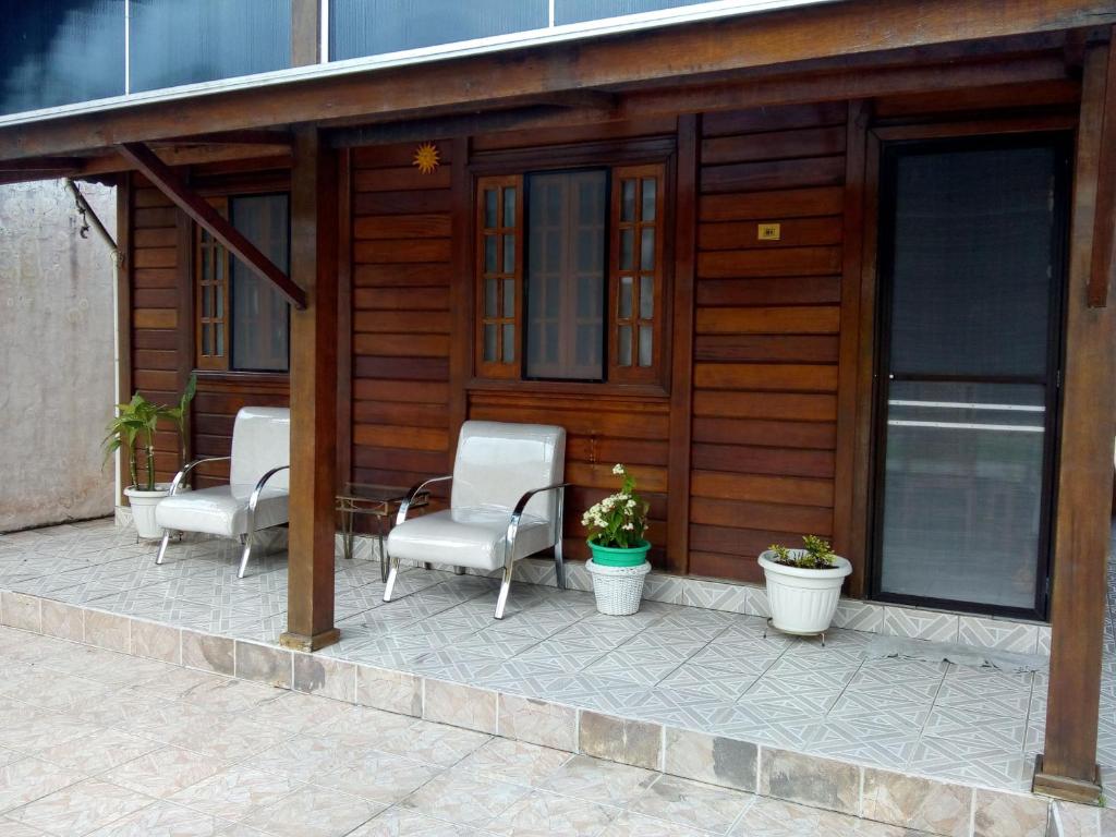 zadaszone patio z krzesłami i roślinami przed budynkiem w obiekcie Ilha Comprida-Casa Madeira-Conforto Familiar w mieście Ilha Comprida