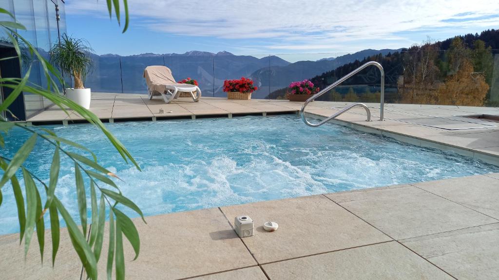 a swimming pool with a chair and mountains in the background at Hotel Monte Bondone in Vaneze