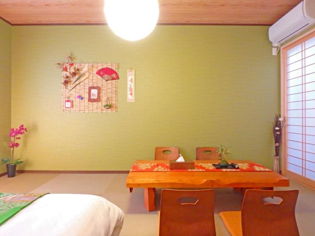 a dining room with a green wall with a table and chairs at Fukenouchi House in Kyoto