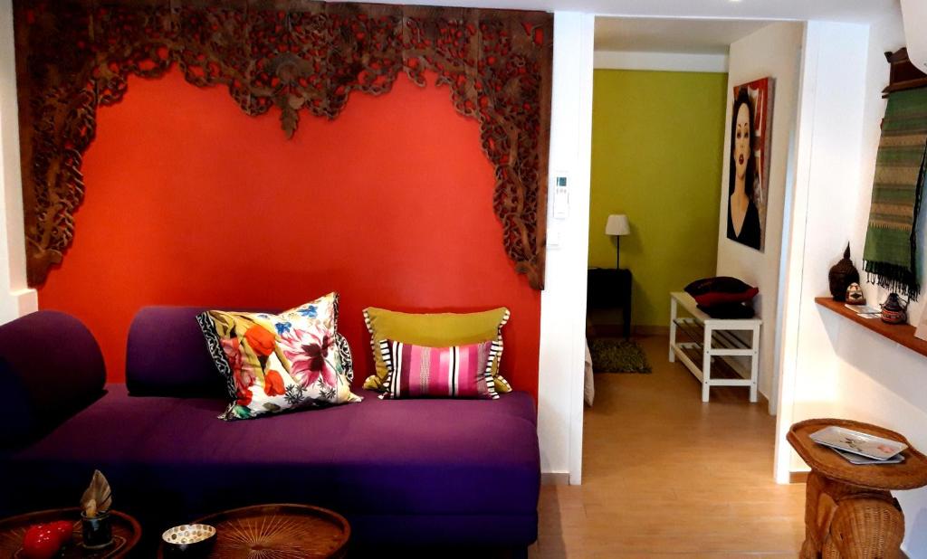sala de estar con sofá púrpura y pared de color naranja en La Grenotte au Castellet, en Le Castellet