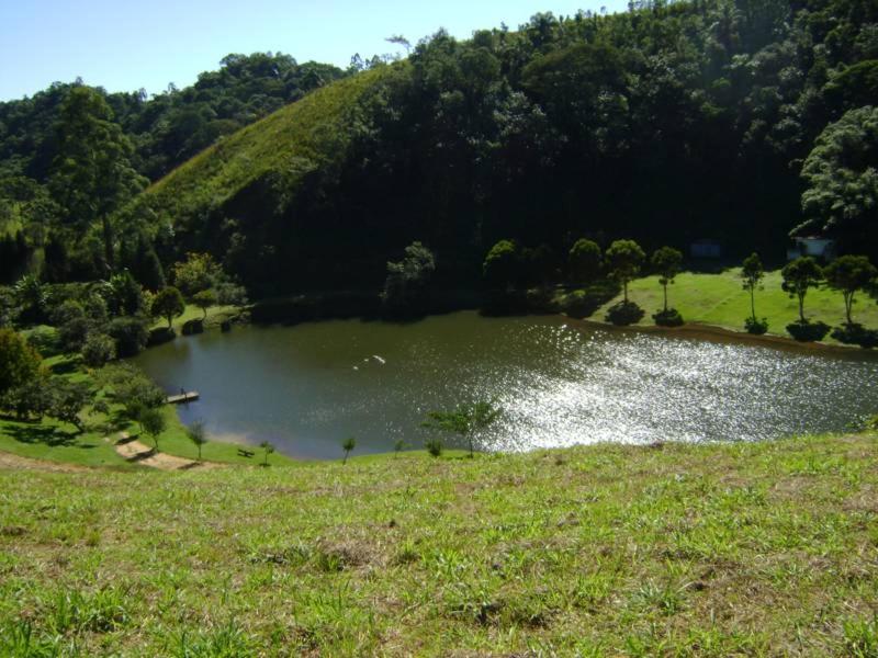 a lake in a field with trees and a hill at Estrela da Serra Hotel Fazenda in Santo Antônio do Pinhal