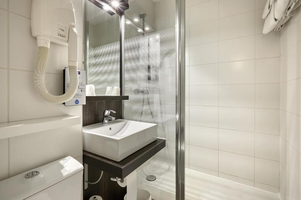 a white bathroom with a sink and a shower at Kyriad La Roche Sur Yon in La Roche-sur-Yon