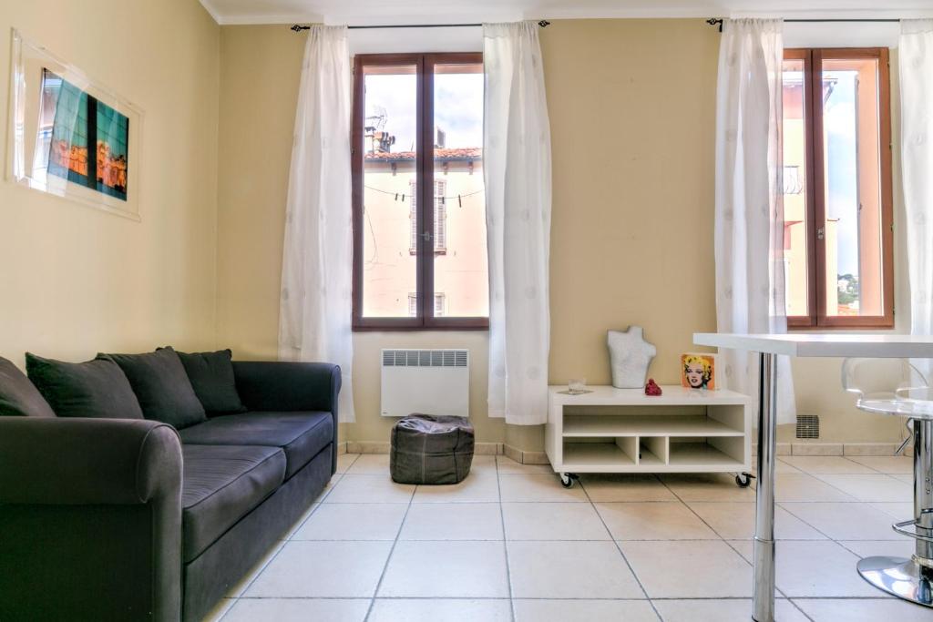 un salon avec un canapé et deux fenêtres dans l'établissement IMMOGROOM - Historic Area Le Suquet - 6min from the beaches, à Cannes