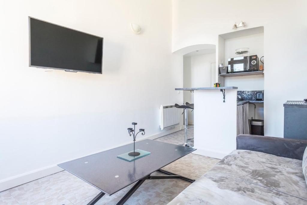 a living room with a table and a tv on a wall at IMMOGROOM - Center - Modern - 10 min from Palais des Festivals in Cannes