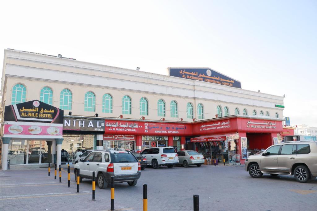 un gran edificio con coches estacionados en un estacionamiento en Al Nile Hotel, en Salalah