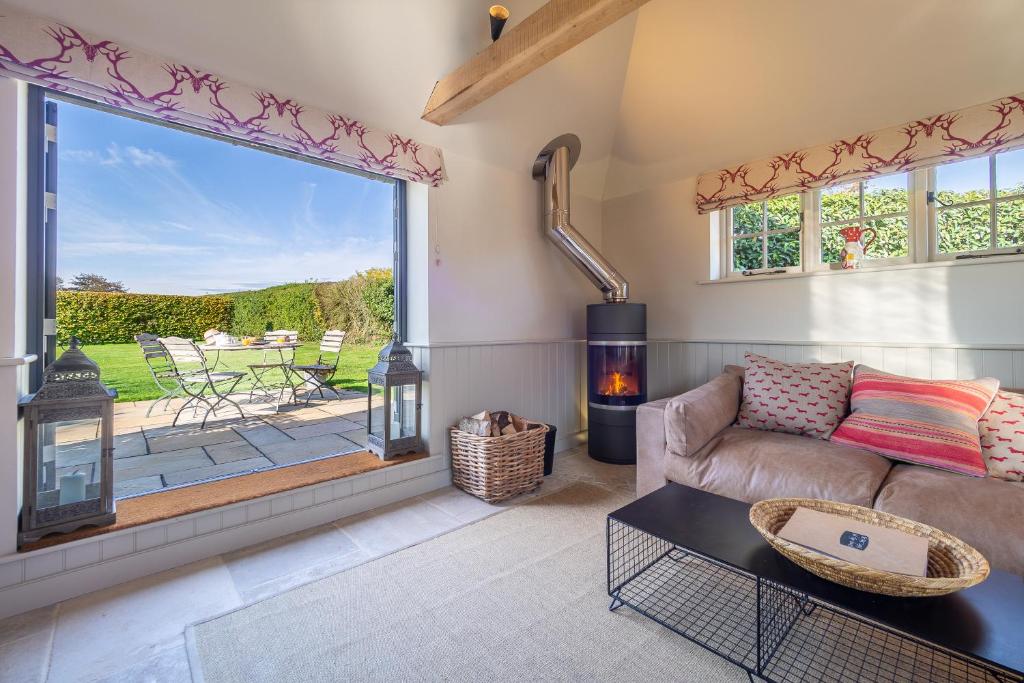 a living room with a couch and a large window at Romantic cottage in pretty village with great pubs - Stoke Cartlodge in Colchester