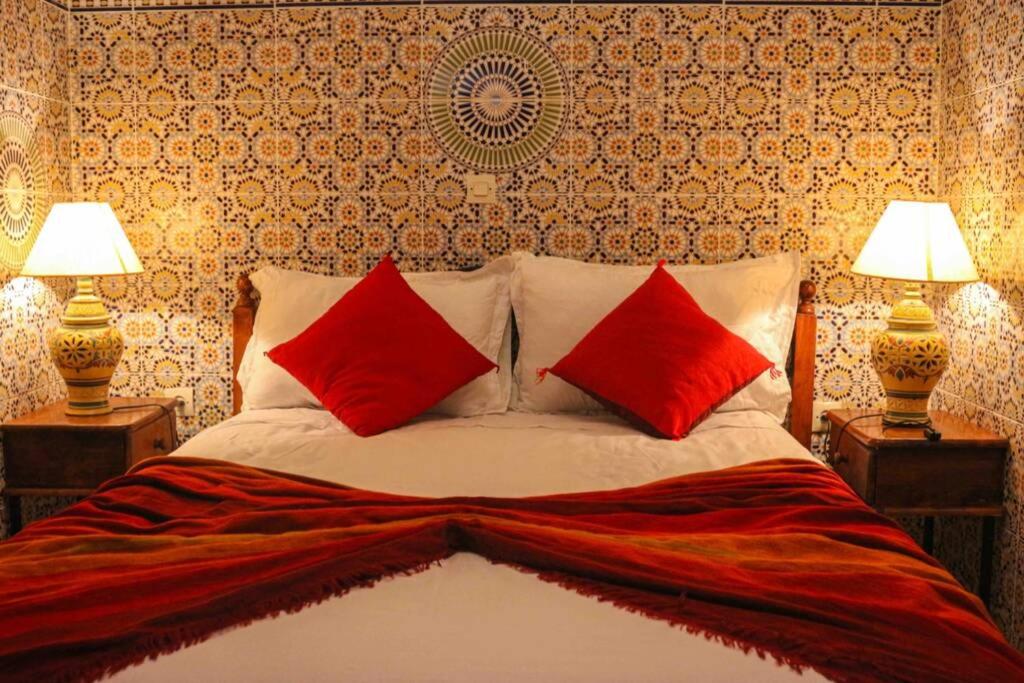 een slaapkamer met een bed met rode kussens en 2 lampen bij Cosy appartement in Marrakesh