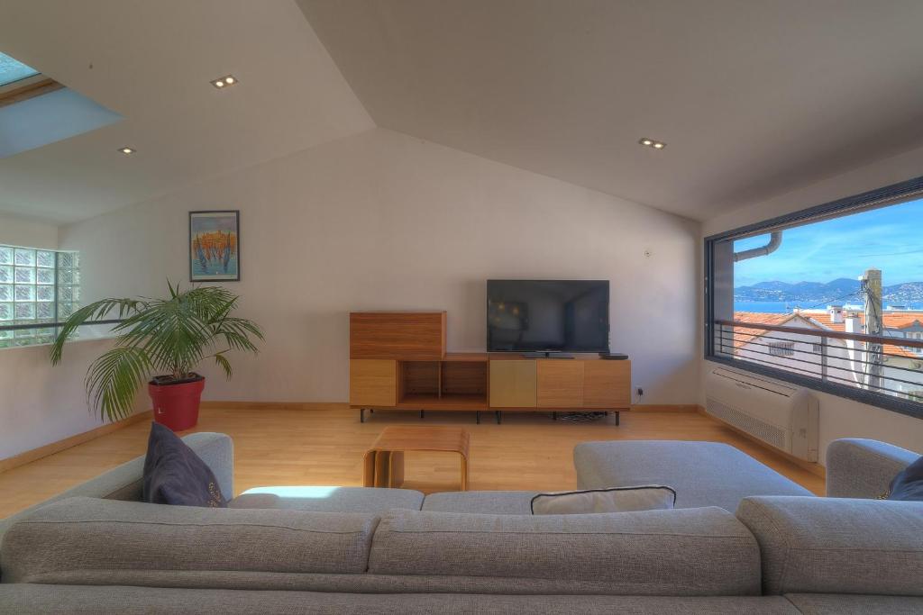 ein Wohnzimmer mit einem Sofa und einem Flachbild-TV in der Unterkunft IMMOGROOM - Beautiful duplex - Sea view - Quiet - AC - Wifi - Garage in Cannes