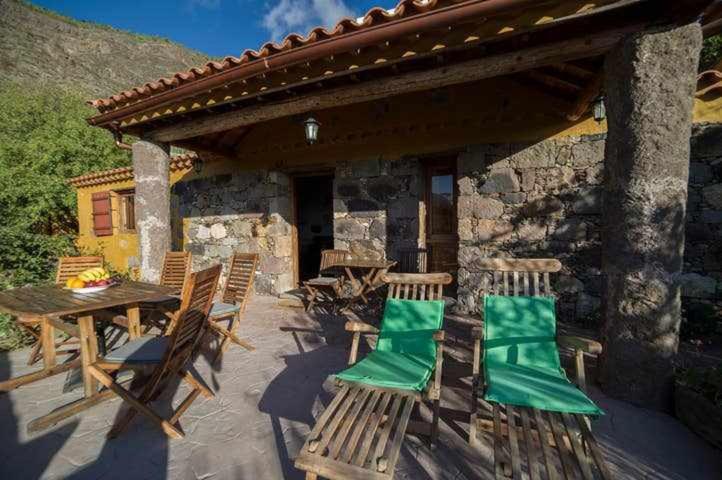a patio with chairs and a table and a building at Casa Rural Cottage Bentayga in Tejeda