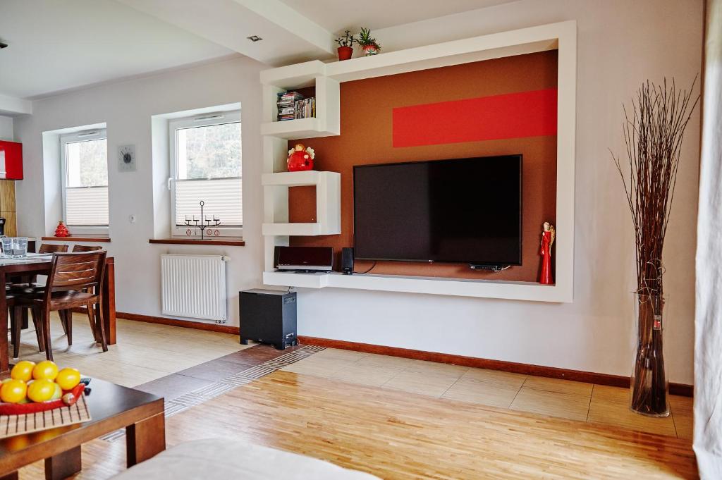 Apartament Bukowa 6 في فيسلا: غرفة معيشة مع تلفزيون بشاشة مسطحة على جدار