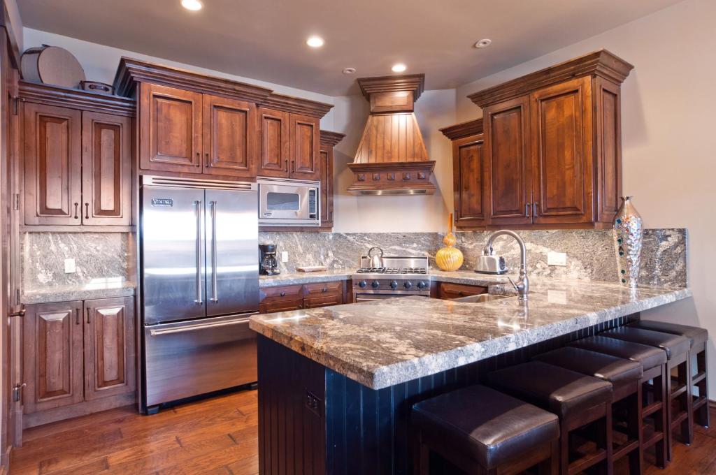 a kitchen with wooden cabinets and a stainless steel refrigerator at Juniper Landing by Lespri Management in Park City