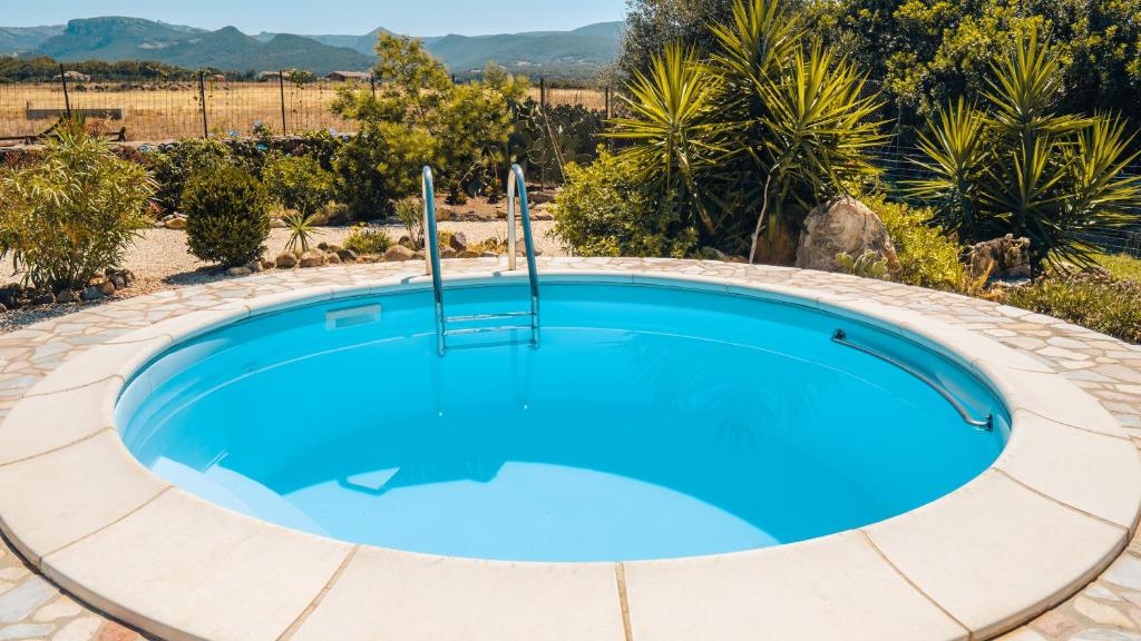a swimming pool in a circle in a yard with trees at Casa Asfodeli - Villetta in campagna con piscina in Cuglieri