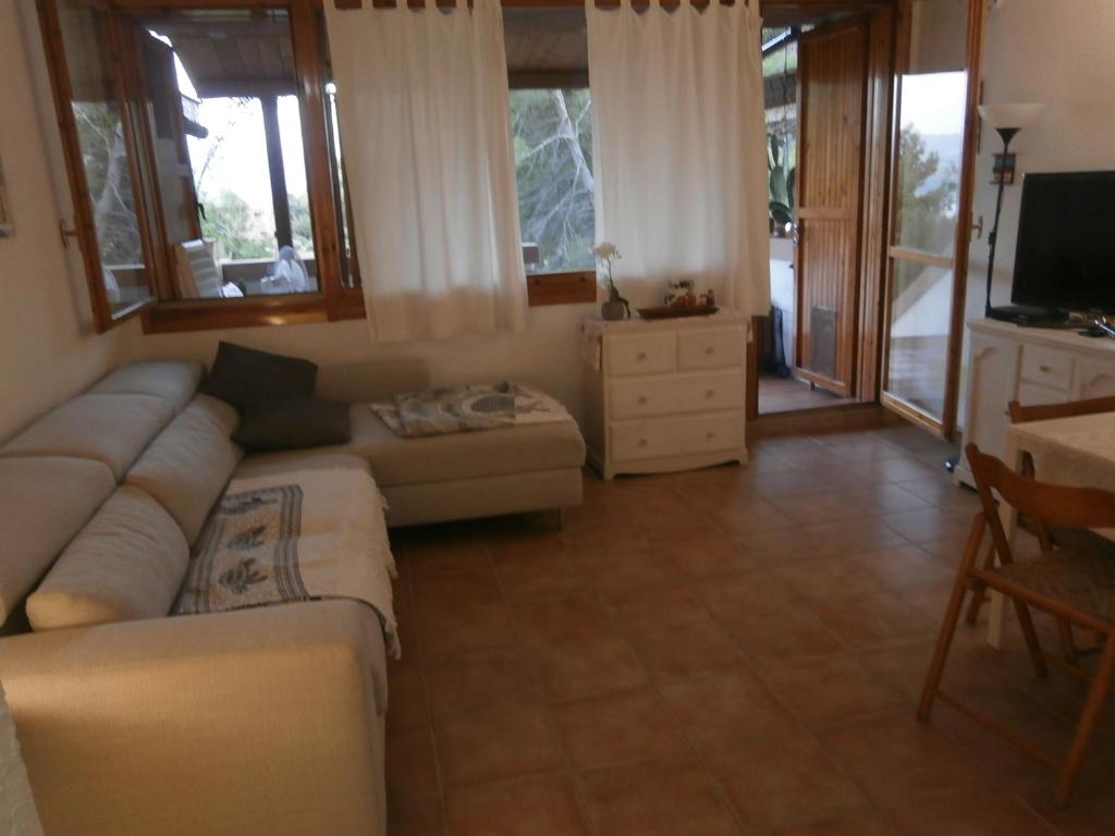 Casa Luciana في Cugnana Verde: غرفة معيشة بها أريكة وتلفزيون