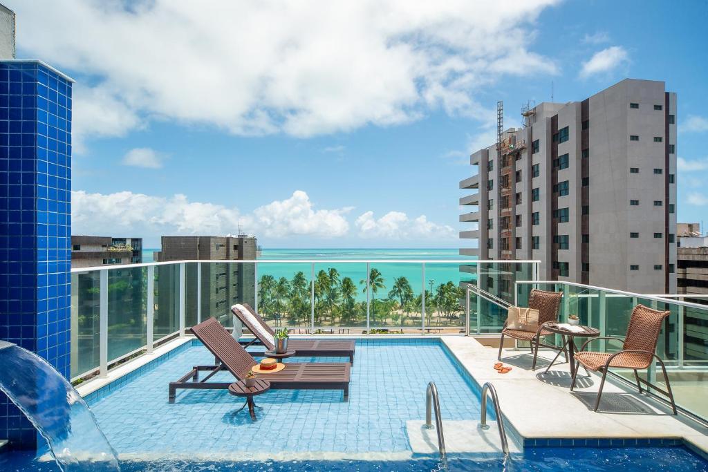 a pool on the roof of a building with a view of the ocean at Tambaqui Praia Hotel in Maceió