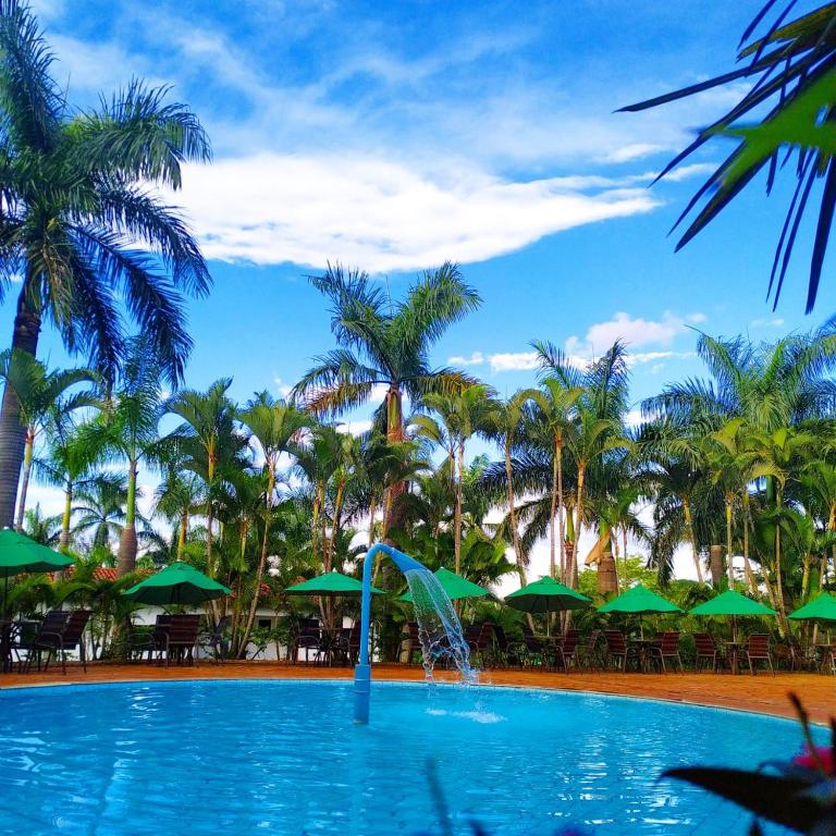 a swimming pool with a fountain in front of palm trees at Hotel Fazenda Vale Amanhecer in Igarapé