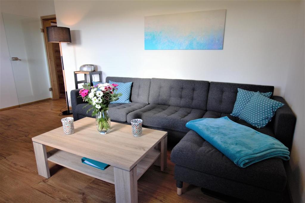 a living room with a couch and a table with a vase of flowers at Ferienwohnung Heideblick in Volkesfeld