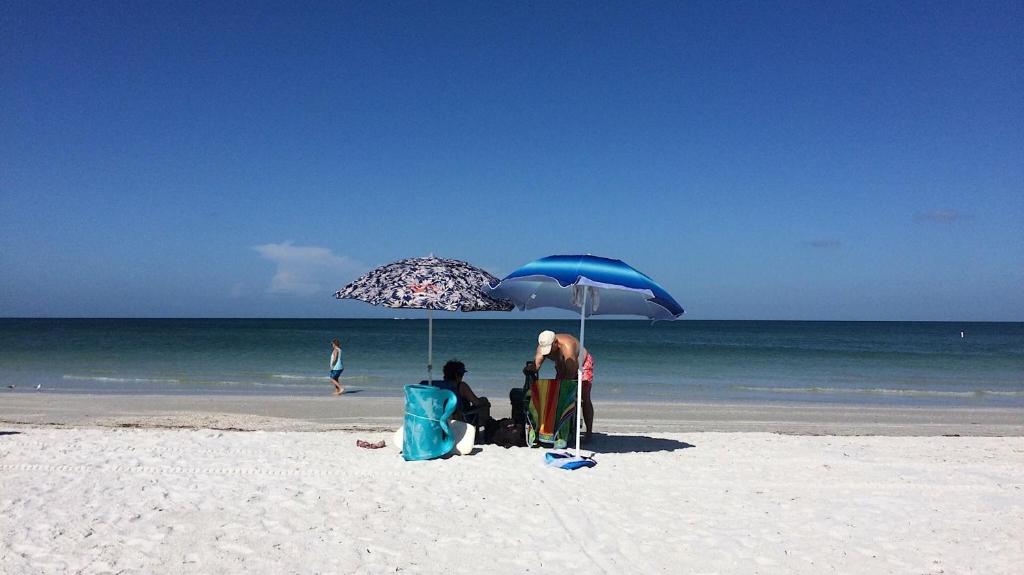two people sitting under an umbrella on the beach at St Pete Vacation Rentals in St. Petersburg