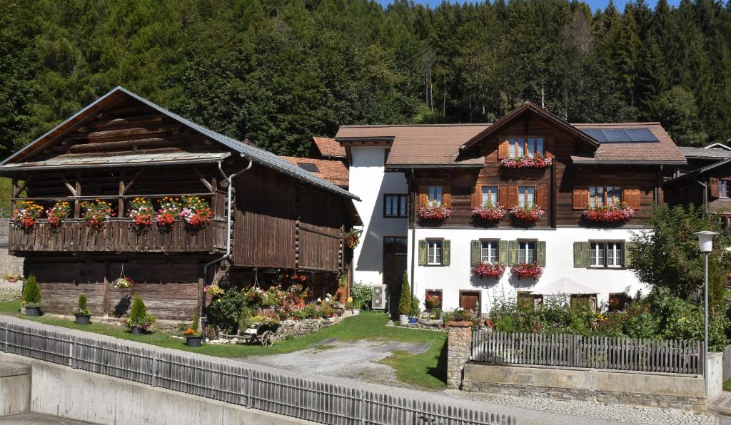 un par de edificios con flores delante de ellos en Casa Curgnun 21 Collenberg - Ferienwohnung 61m2 für max. 4 Pers. en Morissen