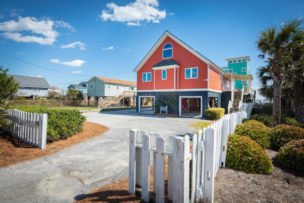 a house with a white fence in front of it at 1709 E Ashley Bacon in the sun in Folly Beach