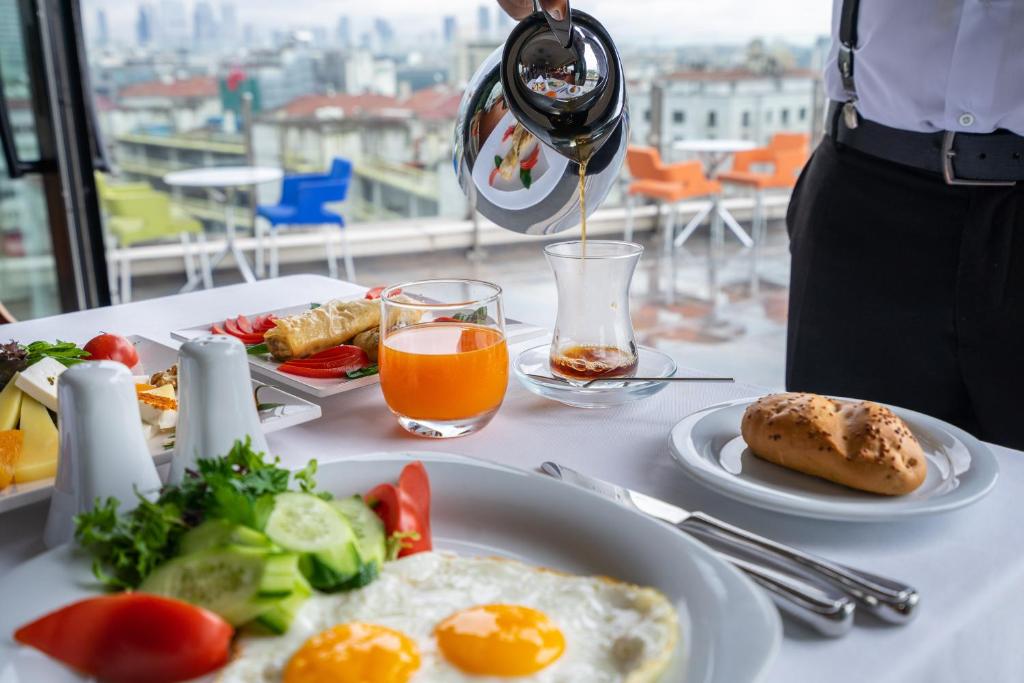 a person pouring a glass of wine over a plate of food at Point Hotel Taksim in Istanbul