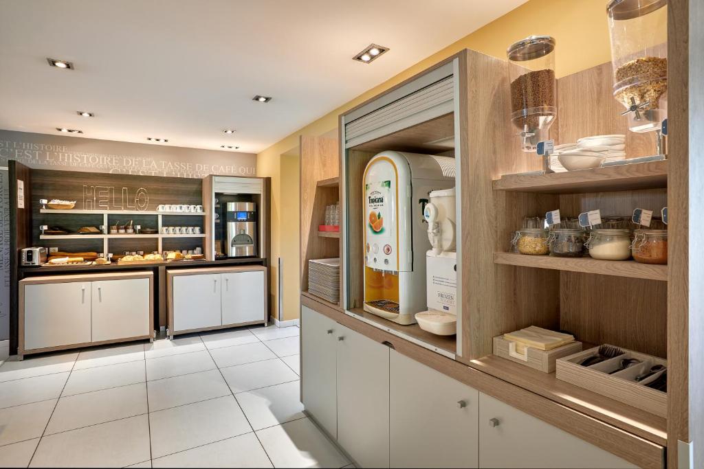 a large kitchen with white cabinets and appliances at Kyriad La Roche Sur Yon in La Roche-sur-Yon