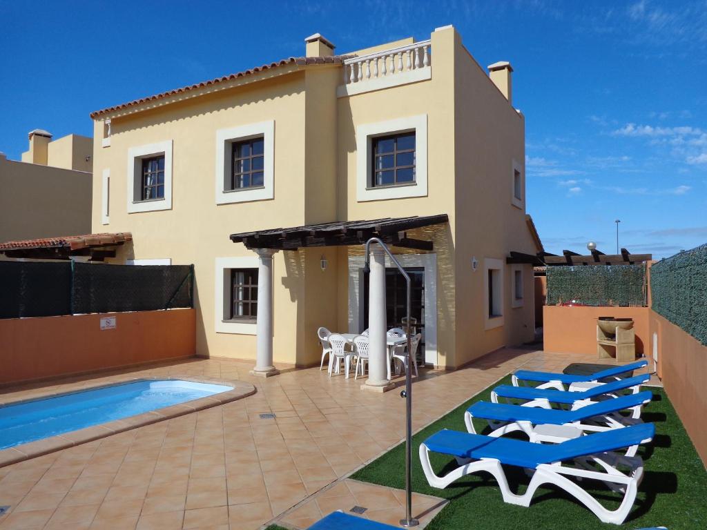 a villa with a swimming pool in front of a house at Casa Miel in Corralejo