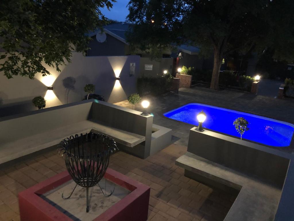 a backyard with a bench and a swimming pool at night at The Homestead in Bloemfontein