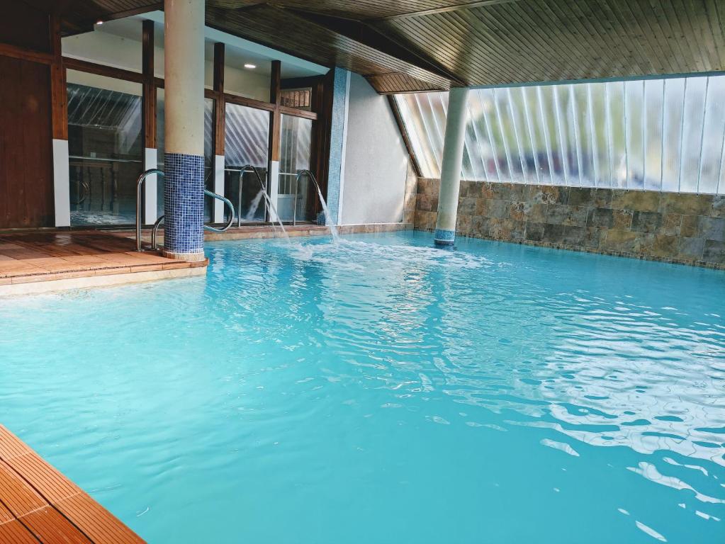 a large pool of blue water in a building at Hotel Ría de Suances in Suances