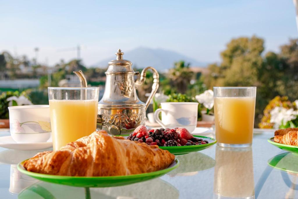 a table with a plate of food and two glasses of orange juice at Jardines Puerto Banus Rooms in Marbella