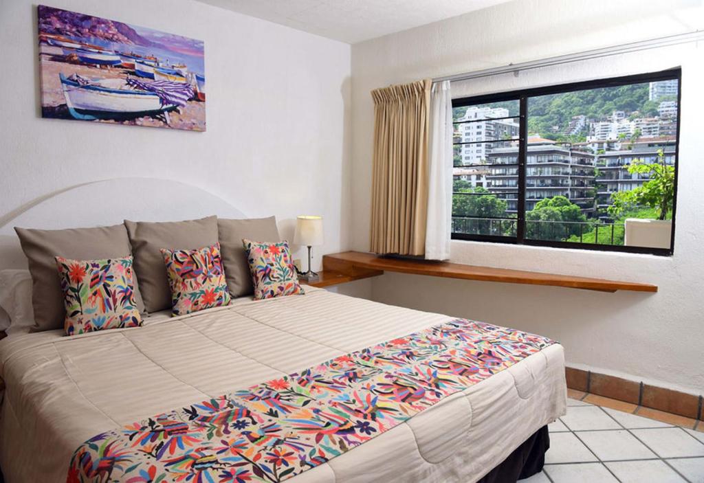 Un dormitorio con una cama grande y una ventana en Hotel Eloisa, en Puerto Vallarta