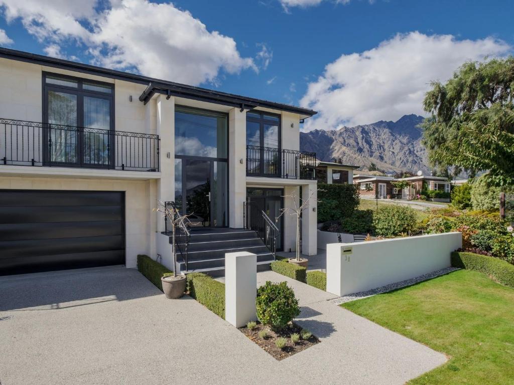 a house with a garage and mountains in the background at Lake Avenue Studio in Queenstown