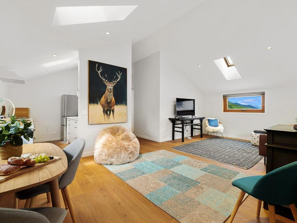 una sala de estar con una mesa y una habitación con una pintura de ciervos en The Loft at Sicilian, en Queenstown