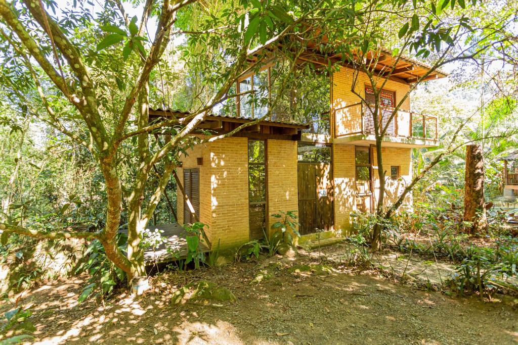 uma casa amarela com uma árvore em frente em Oca Paraty Chalé Ecológico em Paraty