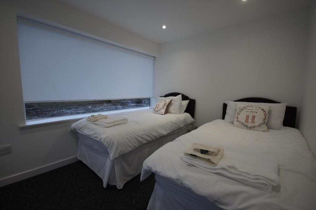 two beds in a room with a window at Loch Lomond Riverside Apartment in Drymen