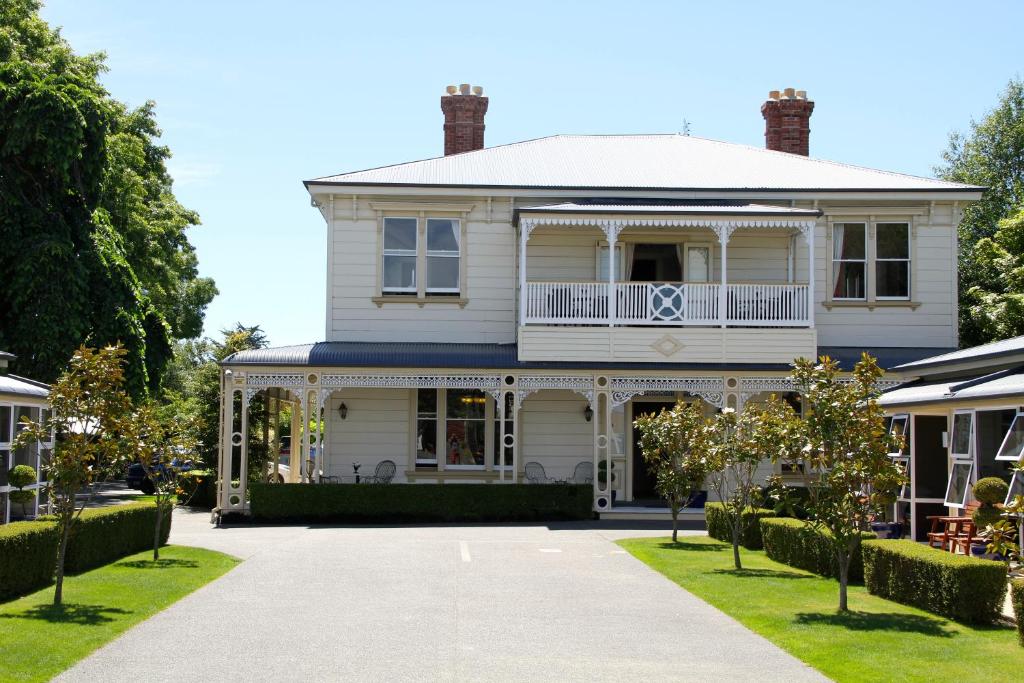 a white house with a porch and a balcony at Merivale Manor in Christchurch