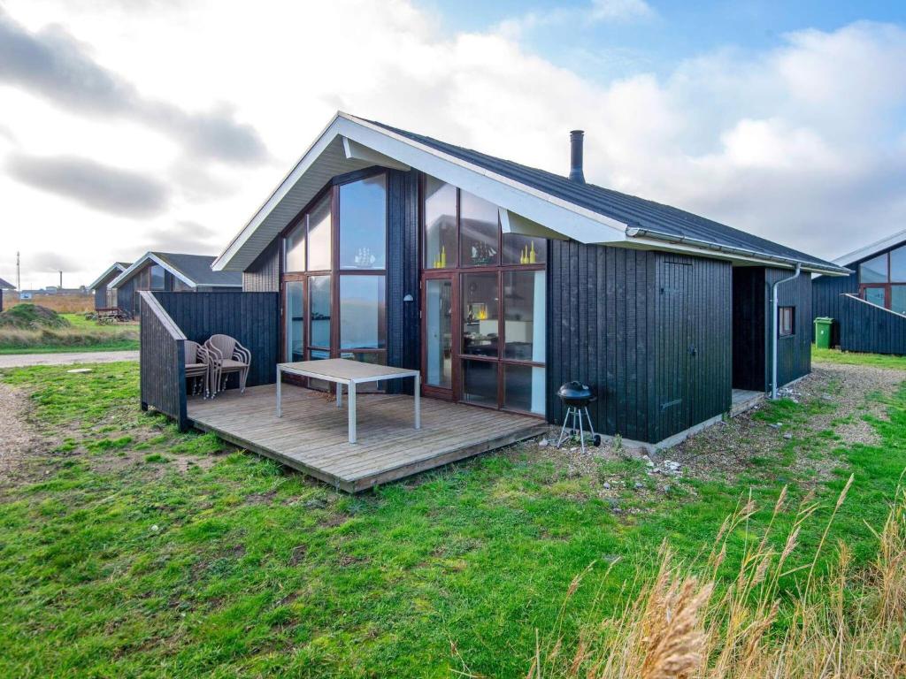 ThorsmindeにあるThree-Bedroom Holiday home in Ulfborg 27の木製デッキ付きの小さな黒い家