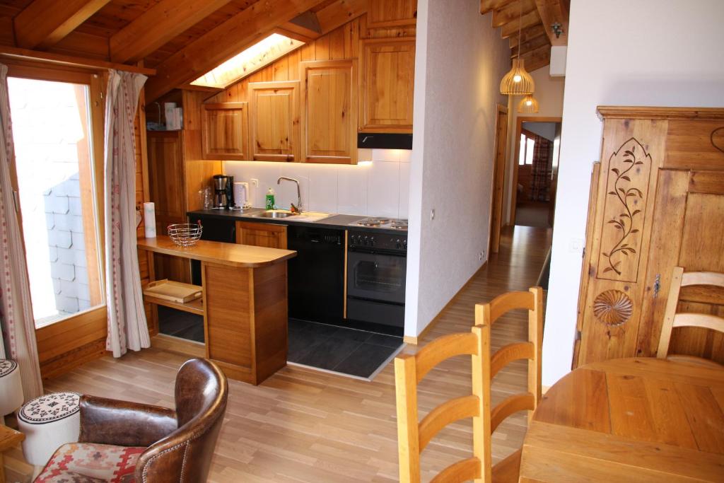 a kitchen with wooden cabinets and a black stove top oven at Meinaz QUIET & SUNNY apartments in Veysonnaz