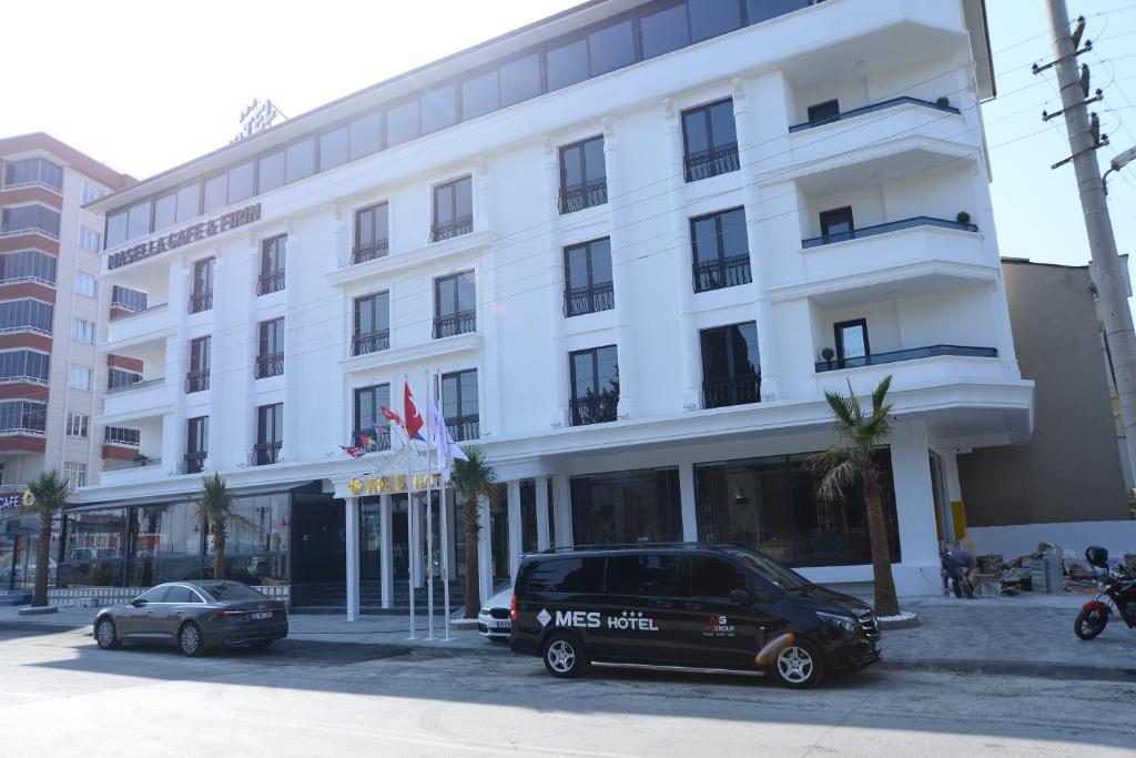 a large white building with cars parked in front of it at Mes Hotel & Spa in Samsun
